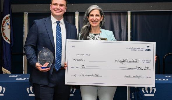 A man holds an award and a woman holds a large-format check for $10,000.