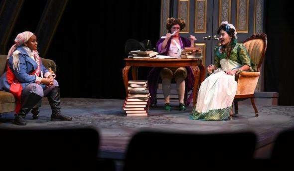 Three women act on a stage.